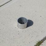 Eine Einbetonierte Bodenhülse, welche ca. 5cm aus dem Beton Herausragt.