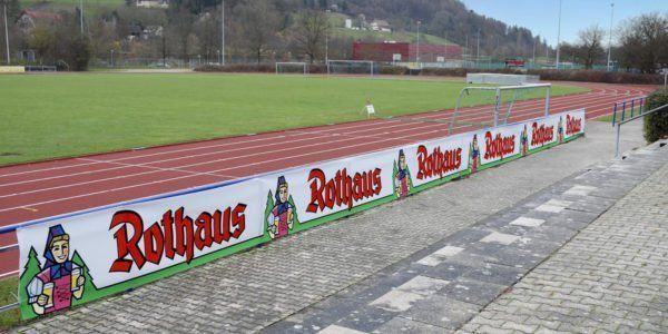 Banner-Werbung aus einem Sportplatz mit Vliesbanner, hier für die Rothaus Brauerei